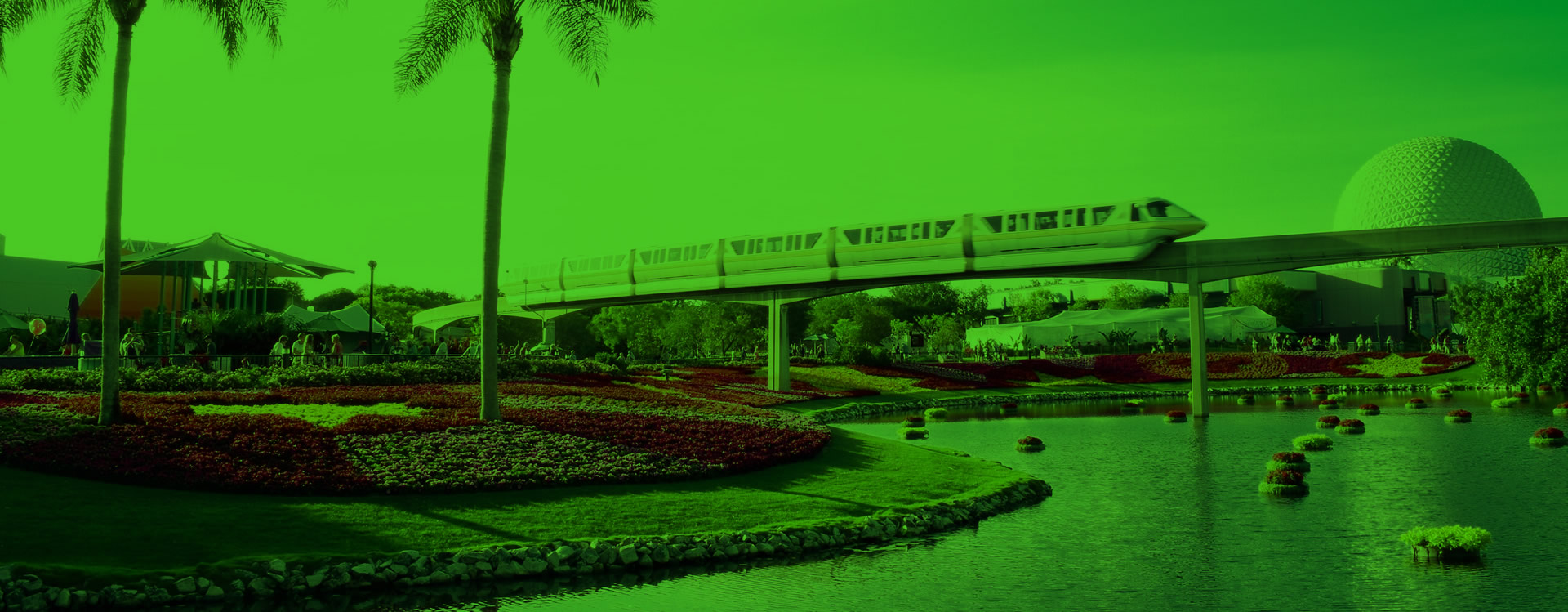 Monorail speeding by on elevated tracks in Disney near a flower garden and pond, with the Epcot dome in the background