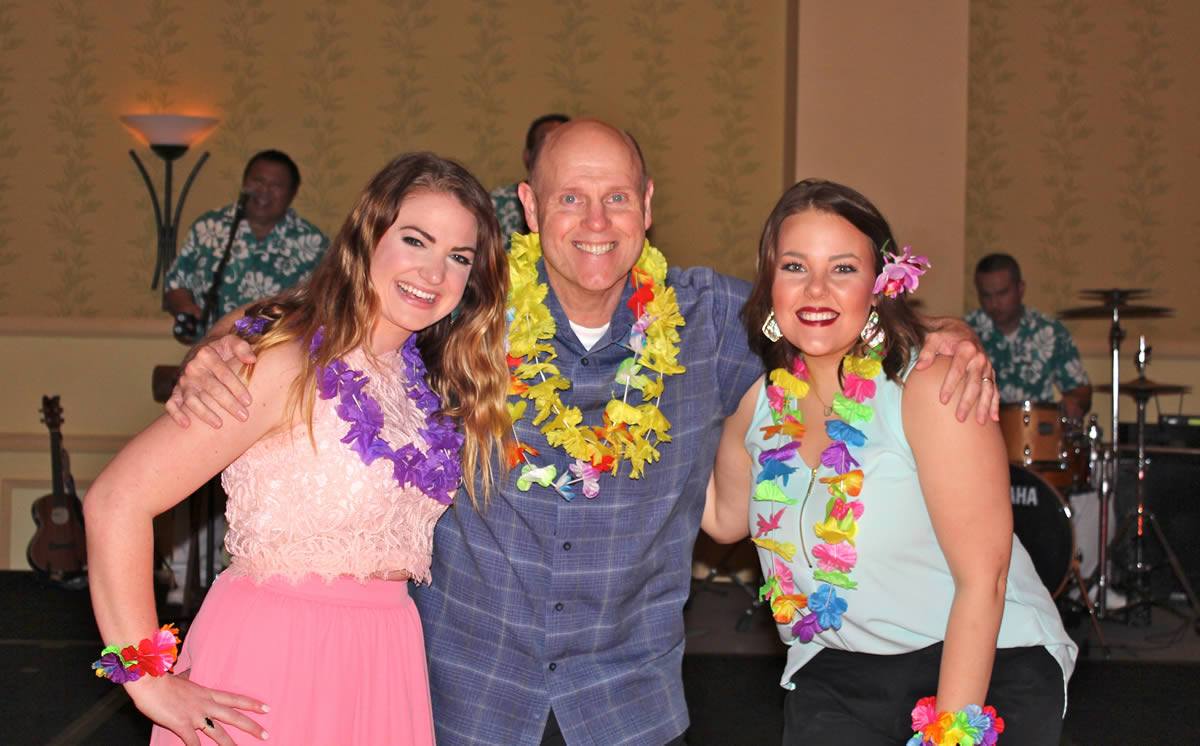 Vendors and guests enjoying music wearing tropical leis around their necks and wrists